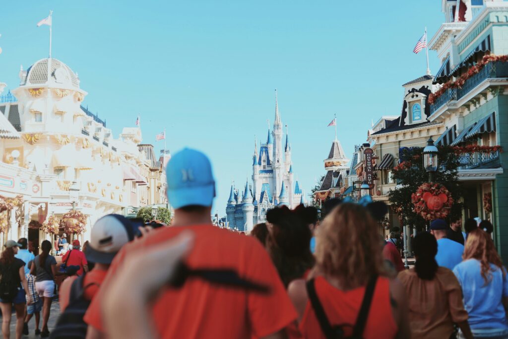 a far away view of the cinderella castle at Disney World with a crowed of people walking toward it