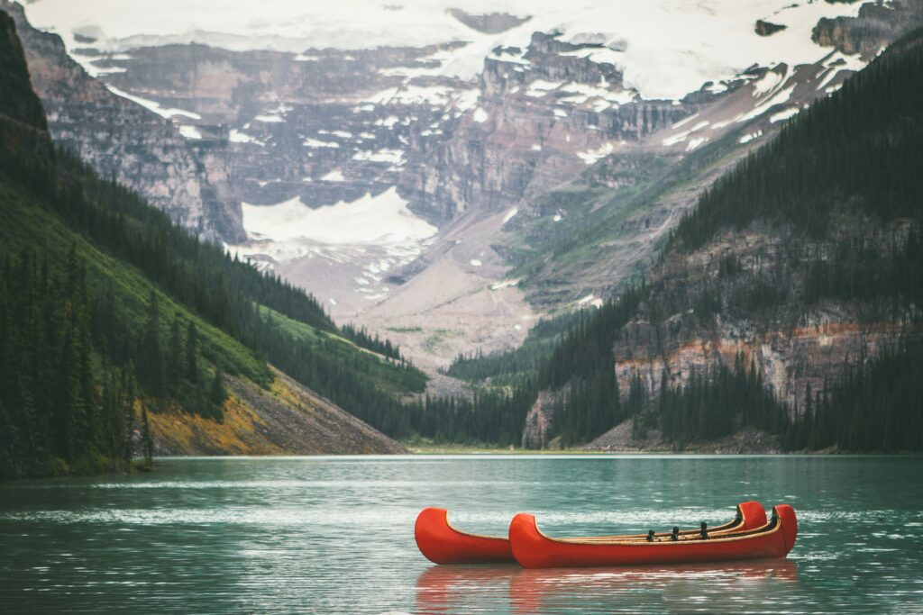 Two red canoes floating in an alpine lake beneth a mountain in Canada