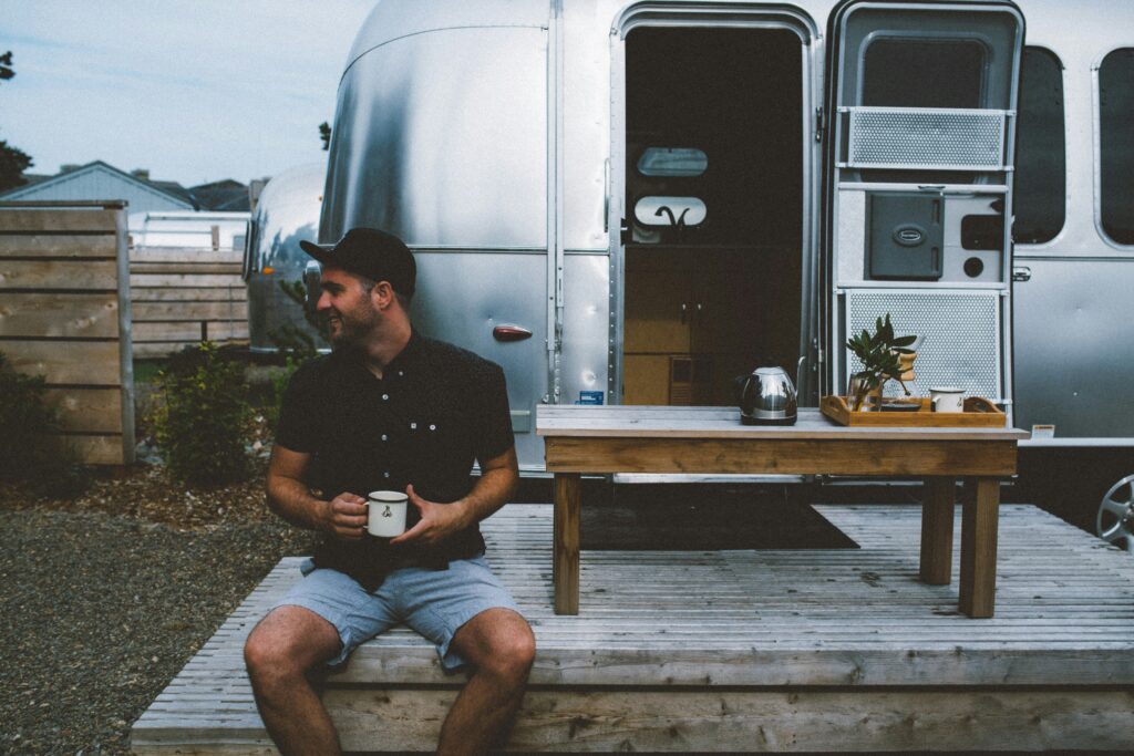 A man having coffee outside his airstream while parked at a campground