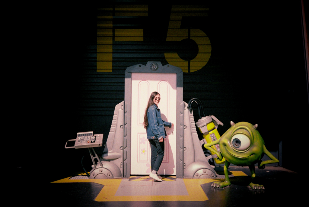 a women poses in front of a door from the movie monsters Inc