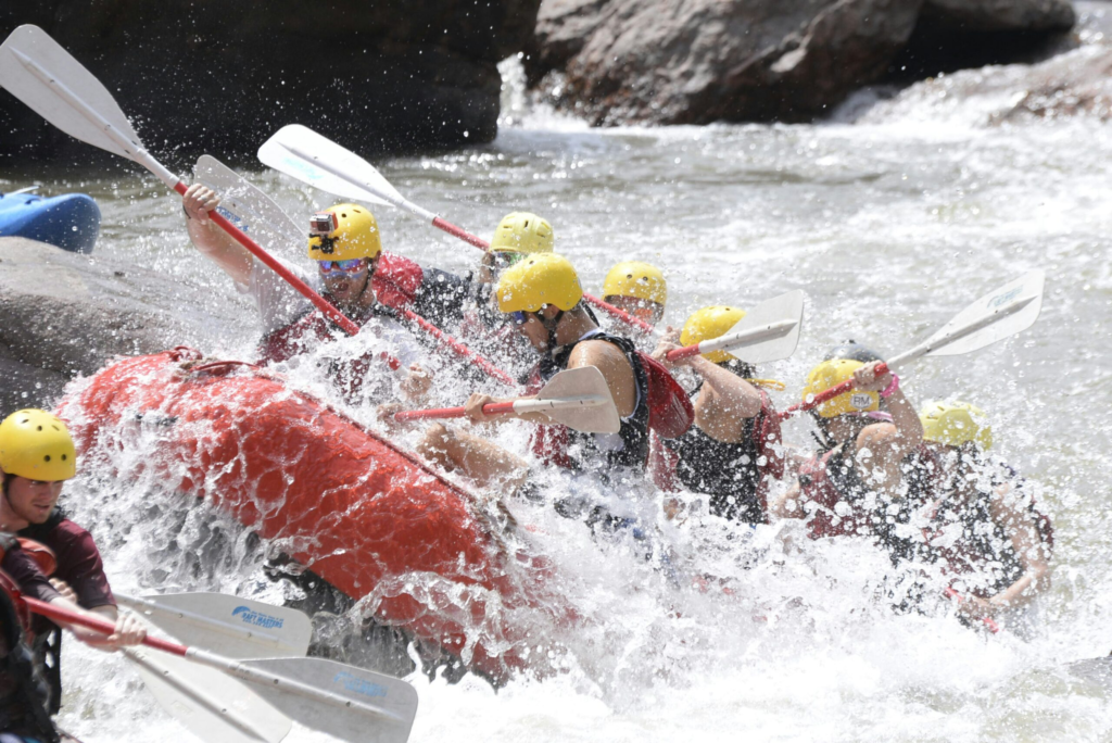 a read rafting boat gets overtaken by a large rapid in a canyon