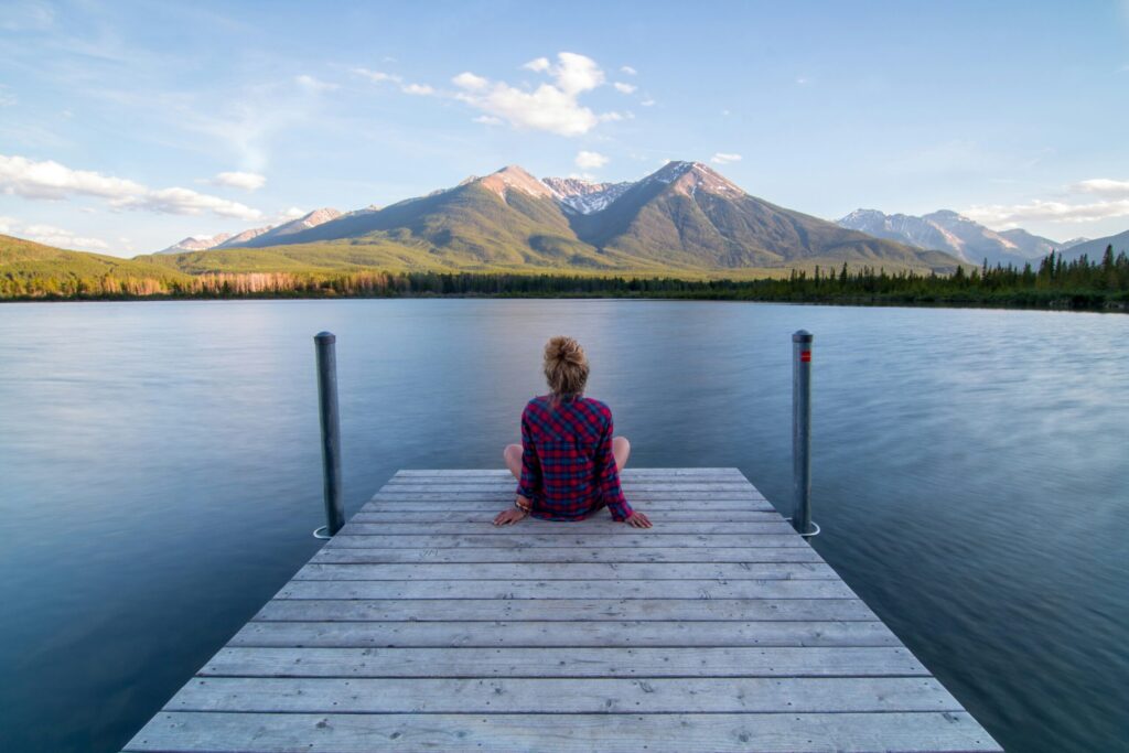Woman sitting on a dock while working a seasonal job under the mountains