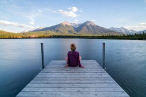 Woman sitting on a dock while working a seasonal job under the mountains