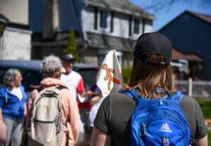 a group following a tour guide who is holding a flag while walking in a small town