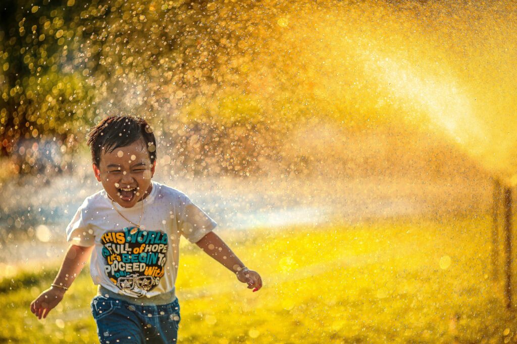 child running through sprinkler