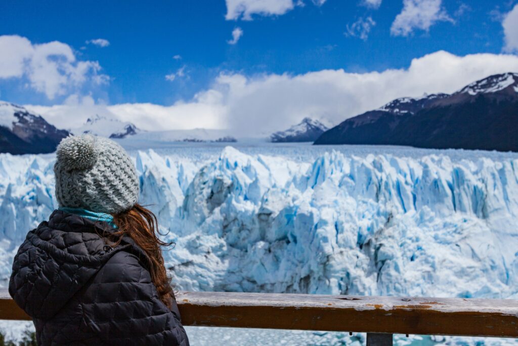 a women stands on a balcony overlooking a glacier in Alaska