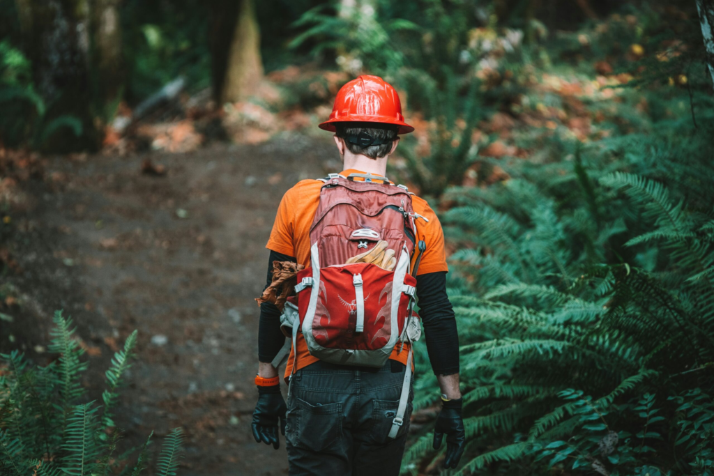 conservation corps member walking a forrest trail with his gear