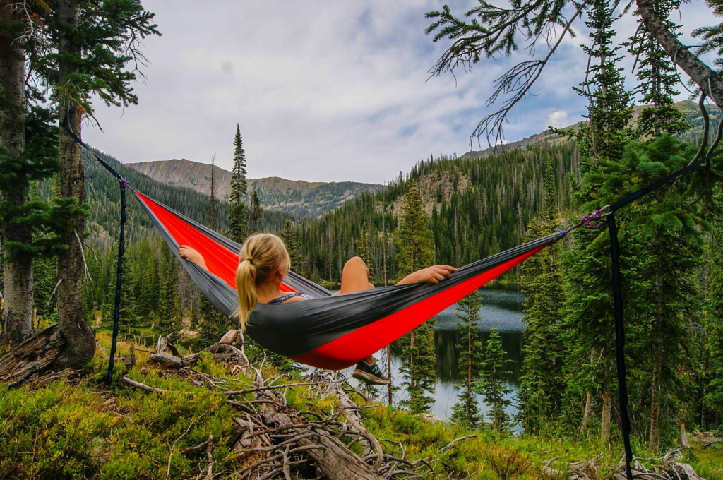 a women sitting on a hammock overlooking a mountain range