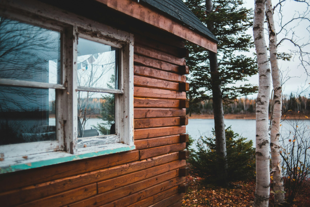 Wooden cabin between aspen trees overlooking a lake in the summer time