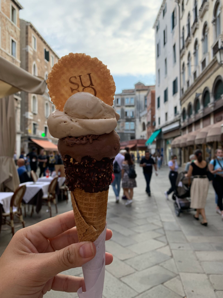 gelato cone held up over a venice street