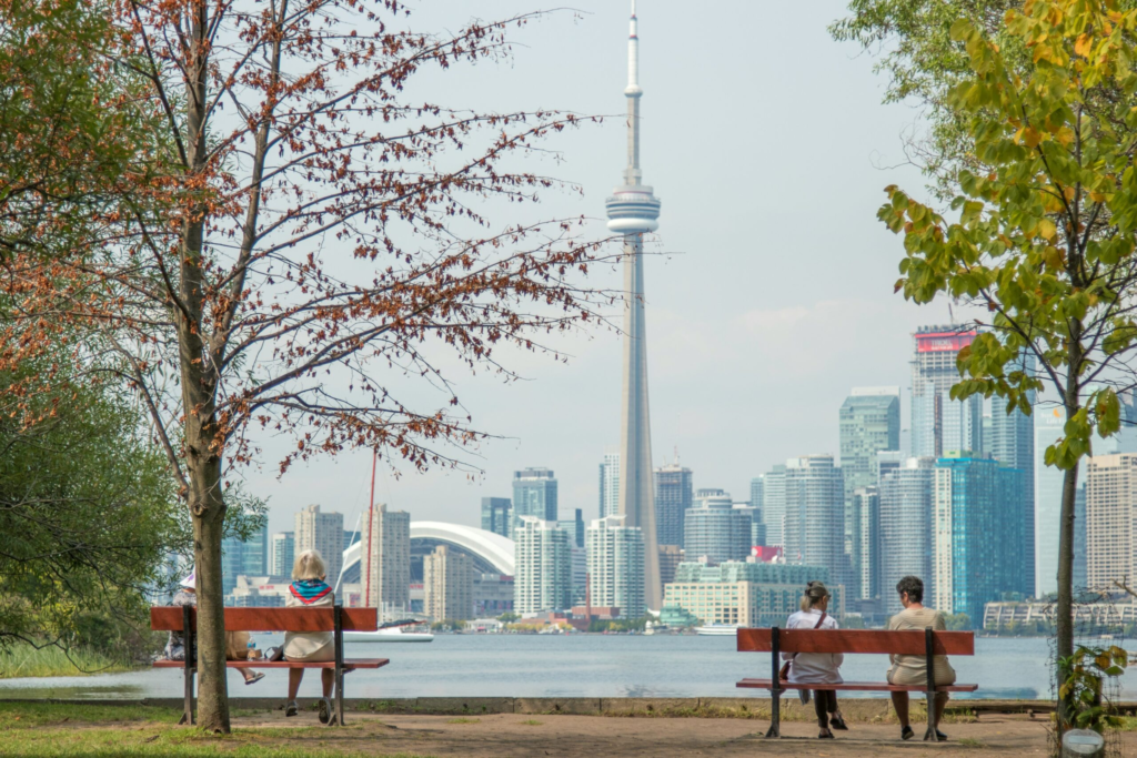 two people sit on a park bench overlooking the city skyline of Toronto
