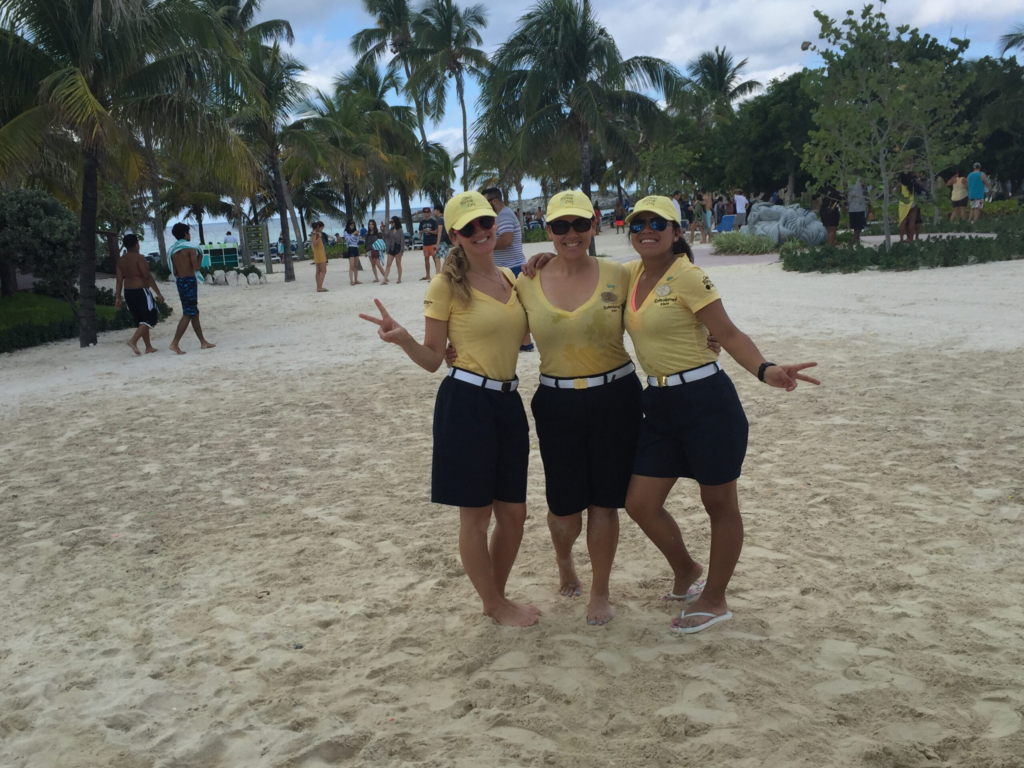 Three youth staff from a cruise ship pose for a photo while working on an island