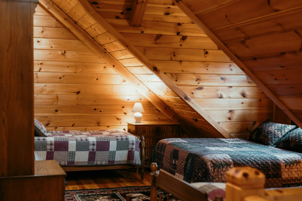 a small wooden bedroom with three ready made beds