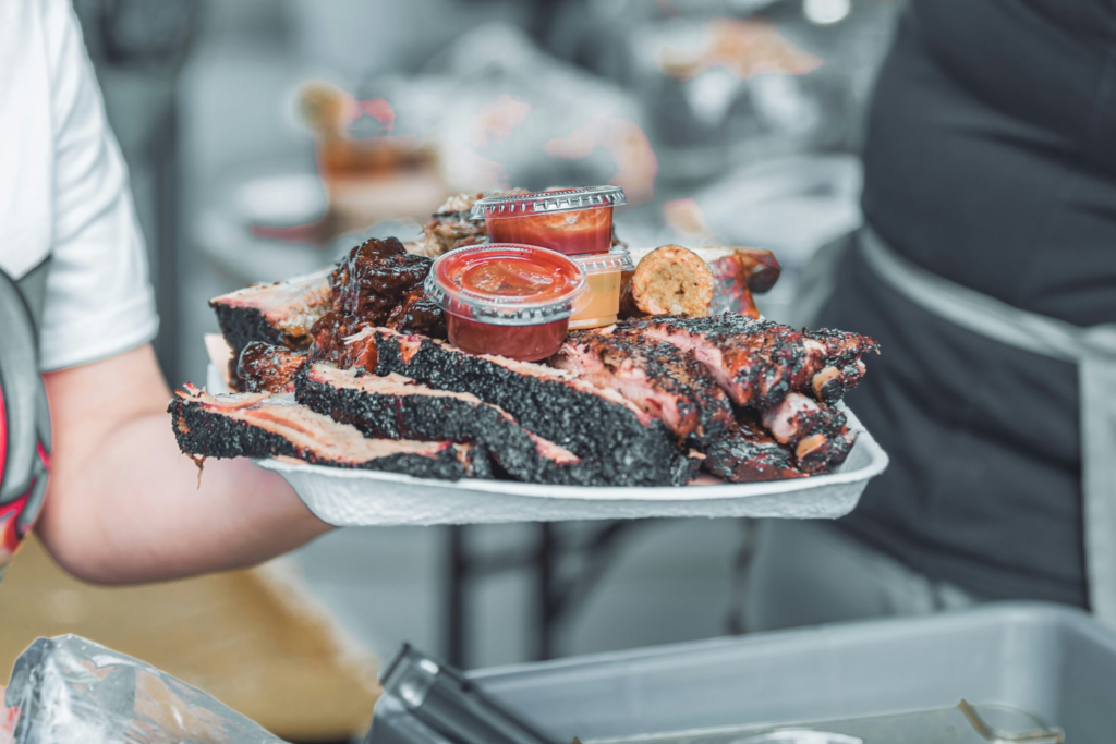 a server hold a large plate of ranch style BBQ ready to eat