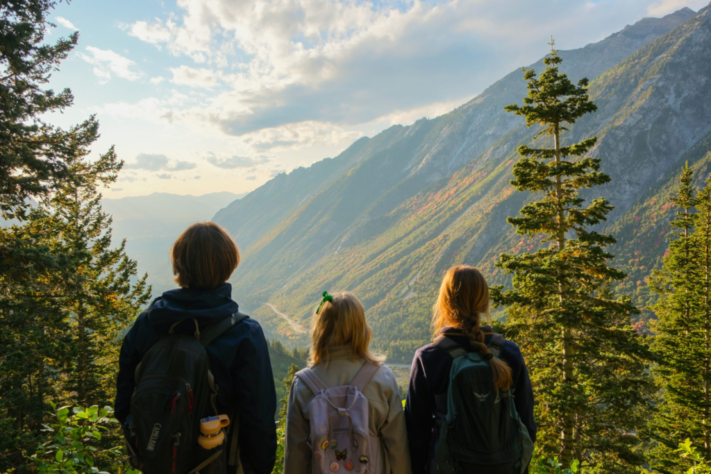 three teens overlook a green mountain range after a hike