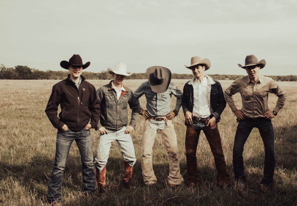 a group of ranch hands pose for a photo while dressed in western attire