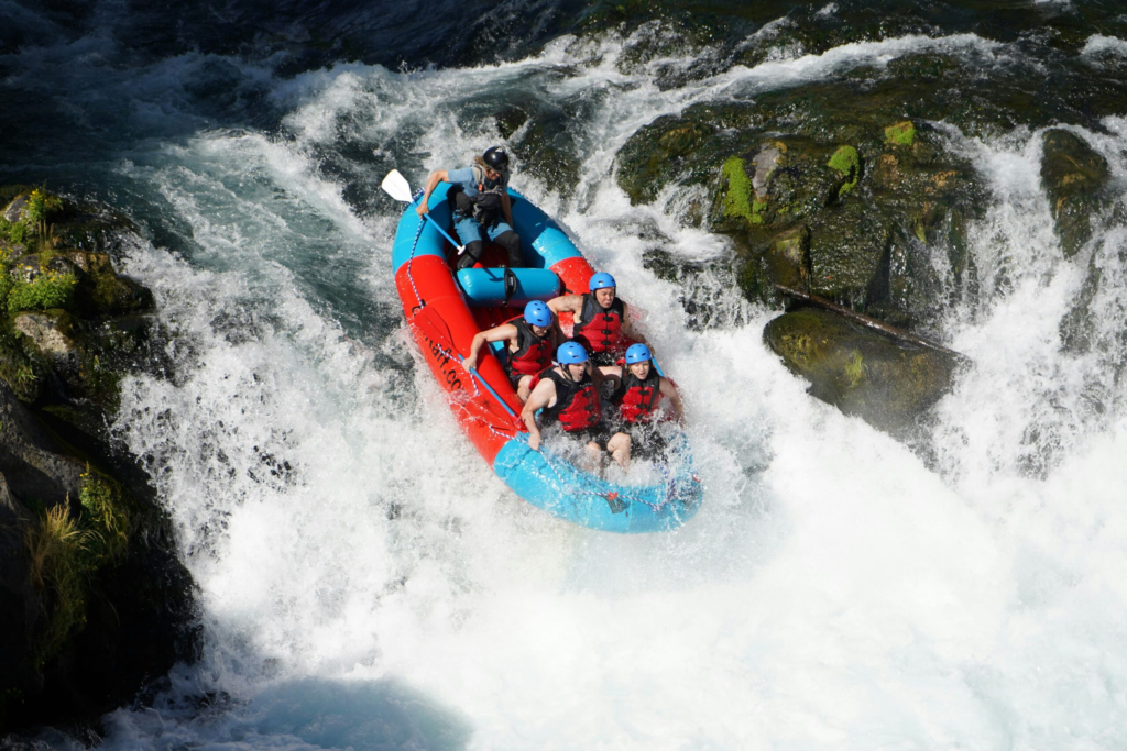 a raft guide takes a group of guests down a class 3 rapid